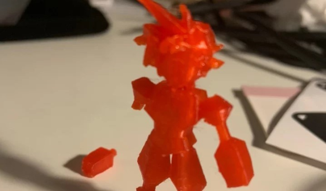 miniature with broken arm printed using red material for 3D printing