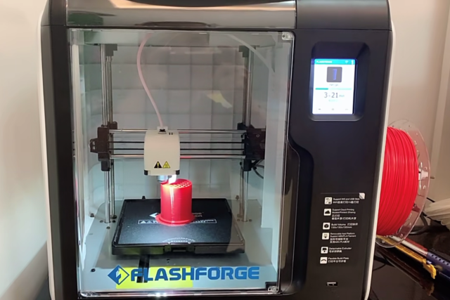 A high speed 3d printer printing a red cylinder